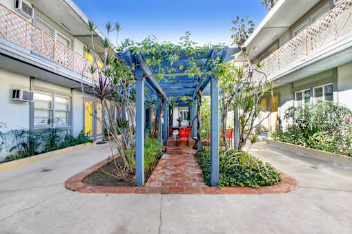 A walkway with a blue canopy and plants on either side.