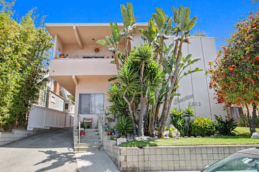 A white two-story house with a balcony on the second floor.