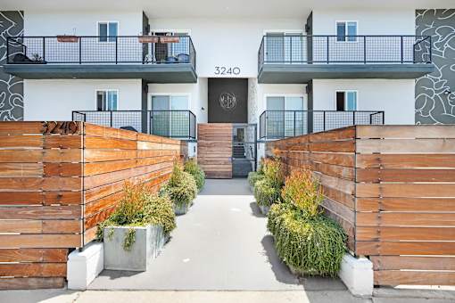 A modern building with a black door and windows, surrounded by wooden fences and plants.