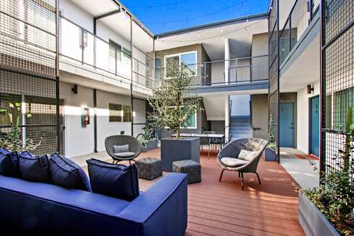 A blue couch is on a wooden deck in front of a building.