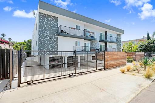 A modern two-story house with a white and grey exterior and a black metal fence.