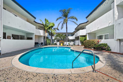A swimming pool in a courtyard surrounded by white buildings.