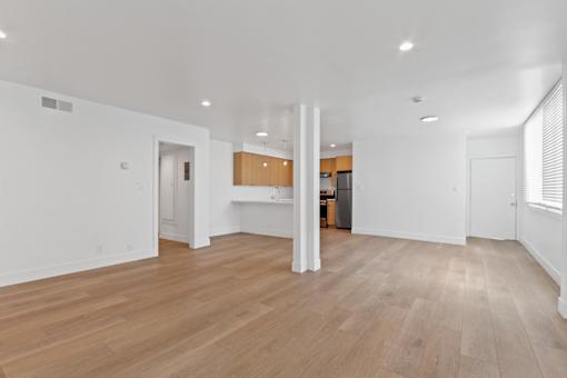 A spacious room with wooden flooring and white walls.