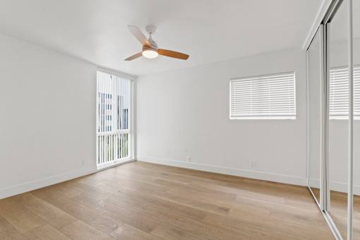 A room with a ceiling fan and wooden flooring.