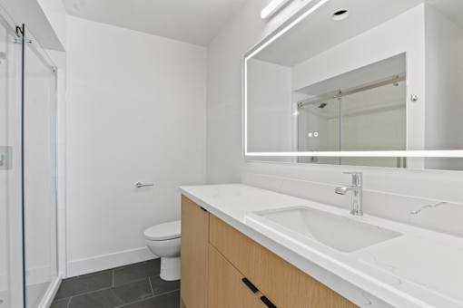 A white bathroom with a toilet, sink, and mirror.