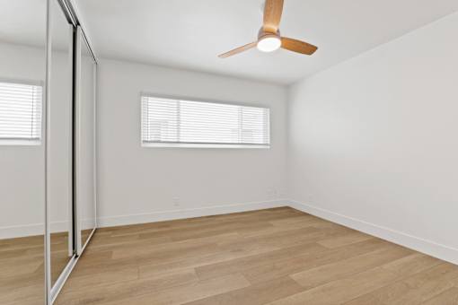 A room with a ceiling fan and a window with blinds.