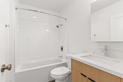 A white bathroom with a toilet, sink, and shower.