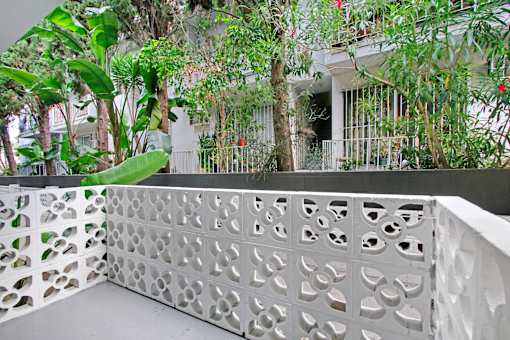 A white lattice fence with circular cutouts separates a patio from a lush green garden.