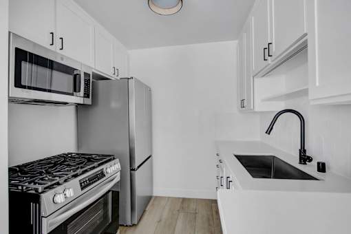A kitchen with white cabinets and a black stove top oven.