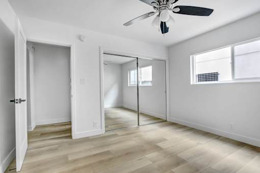 A room with a ceiling fan and sliding glass doors.