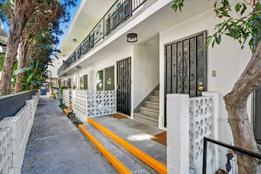 A white building with a black gate and a yellow line on the sidewalk.