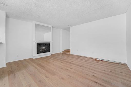 A room with a fireplace and wood flooring.