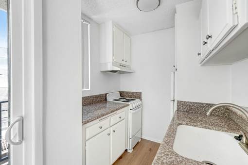 A kitchen with white cabinets and a granite countertop.