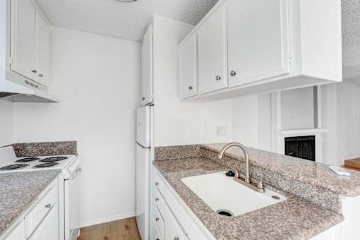 A kitchen with granite countertops and white cabinets.