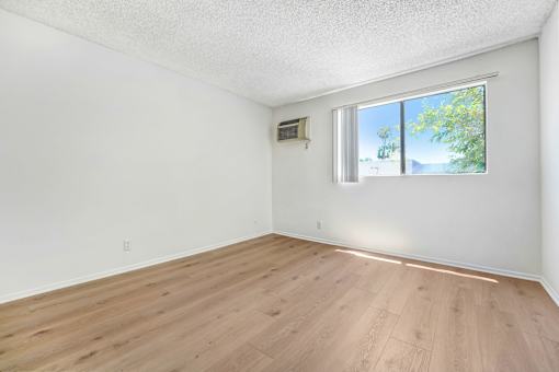 A room with a window and a wall-mounted air conditioning unit.