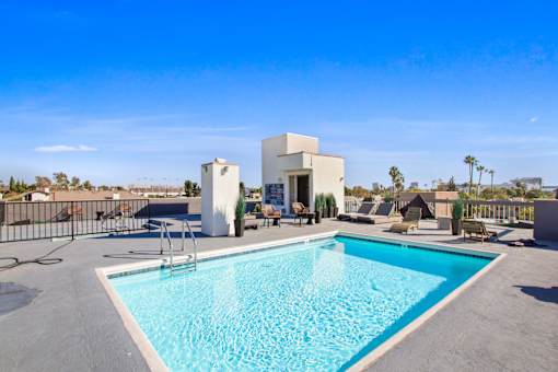 A swimming pool in a backyard with a white building in the background.