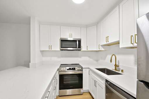 A modern kitchen with white cabinets and stainless steel appliances.