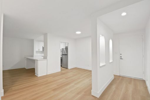 A white kitchen with a refrigerator, sink, and cabinets.