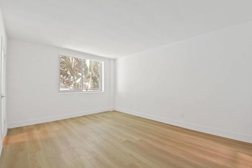 A room with a wooden floor and a painting on the wall.