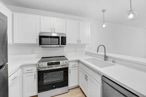 A modern kitchen with white cabinets and stainless steel appliances.