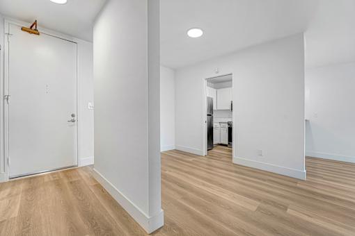 A white room with a wooden floor and a white door.