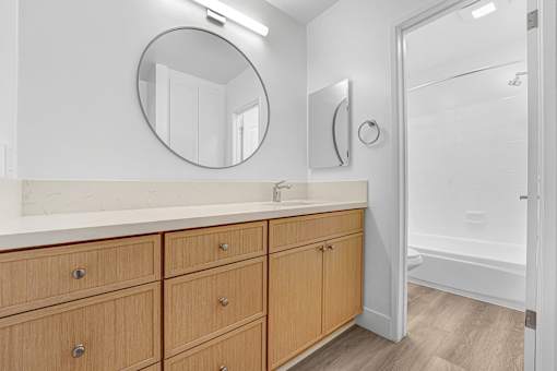 A bathroom with a vanity and a round mirror.