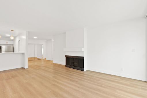 A large, empty room with a fireplace and wooden floors.