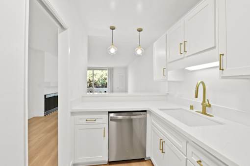 A kitchen with white cabinets and a stainless steel dishwasher.