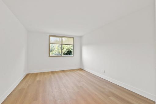 A room with a window and wooden flooring.