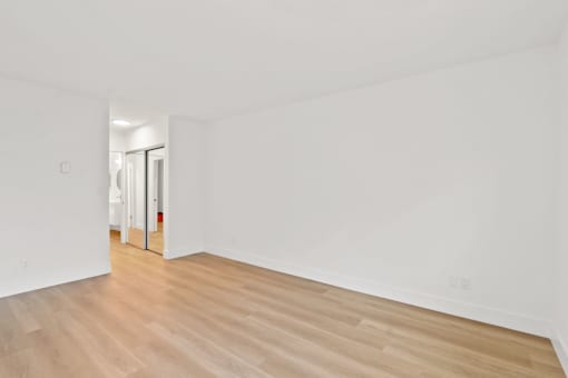 A room with wooden flooring and white walls.