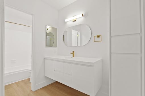 A white bathroom with a sink and mirror.