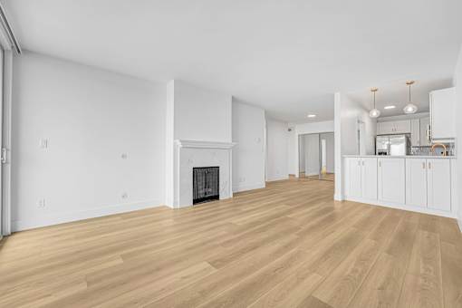 A large, empty room with wooden floors and a fireplace.