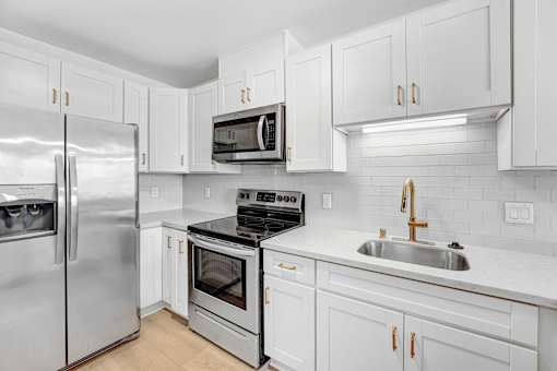 A modern kitchen with white cabinets and stainless steel appliances.