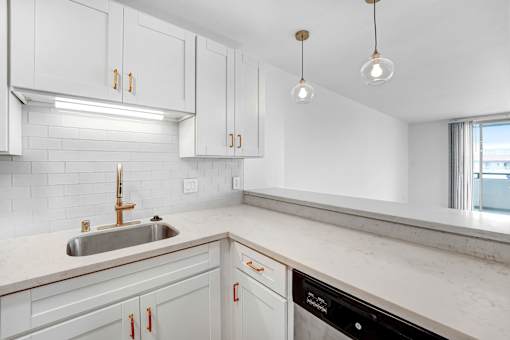 A kitchen with white cabinets and a marble countertop.