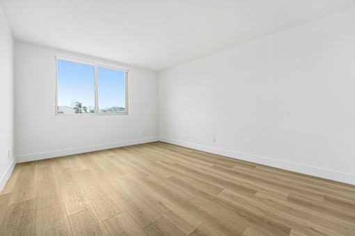 Empty room with wooden flooring and a window.