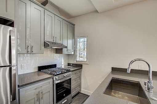 A kitchen with a stainless steel refrigerator, oven, and sink.