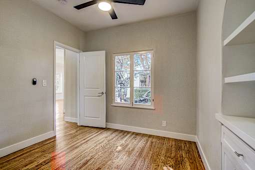 A room with a ceiling fan and a window with a view of trees.