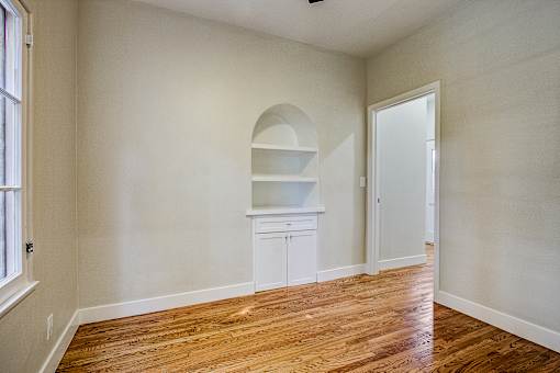 A room with a wooden floor and a white cabinet with shelves.
