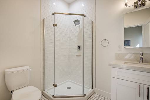A white toilet sits next to a walk-in shower in a bathroom.