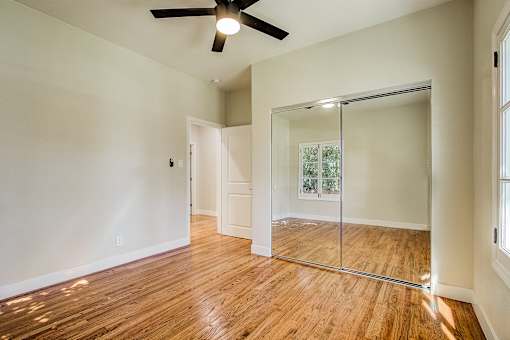 A room with a ceiling fan and a glass door leading to a balcony.