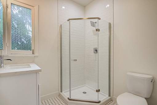 A white toilet sits next to a walk-in shower in a bathroom.