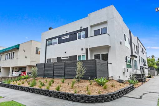 A modern white building with a black fence and a green roof.