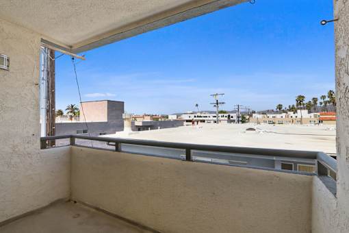 A balcony with a view of a parking lot and buildings.