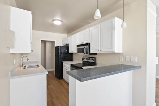 A kitchen with white cabinets and black appliances.