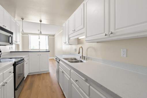 A kitchen with white cabinets and a stainless steel sink.