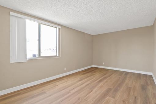 Empty room with wooden flooring and a window.