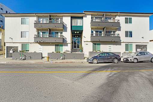 Two cars parked in front of a white apartment building.