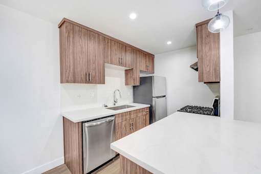 A kitchen with a white countertop and wooden cabinets.