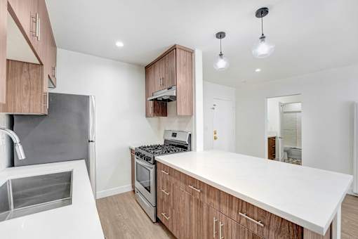 A modern kitchen with a white countertop and wooden cabinets.