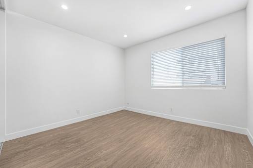 A room with wooden flooring and a window with blinds.
